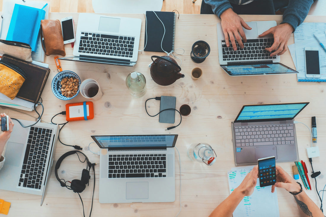 desk with laptops and people typing on them